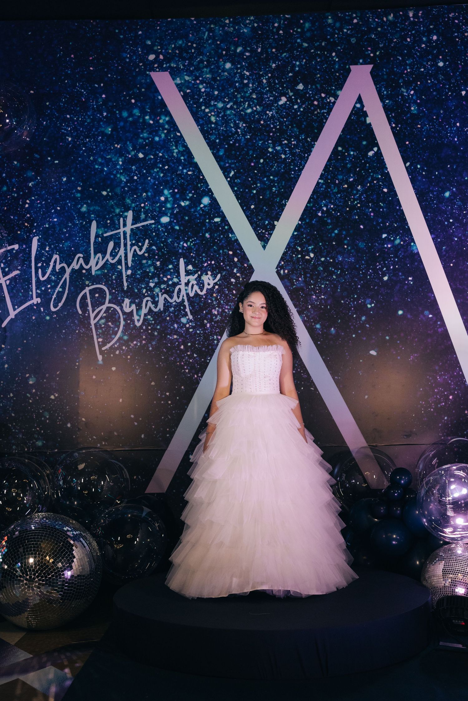 A white tulle wedding gown is displayed against a starry backdrop with geometric decor and illuminated signage.