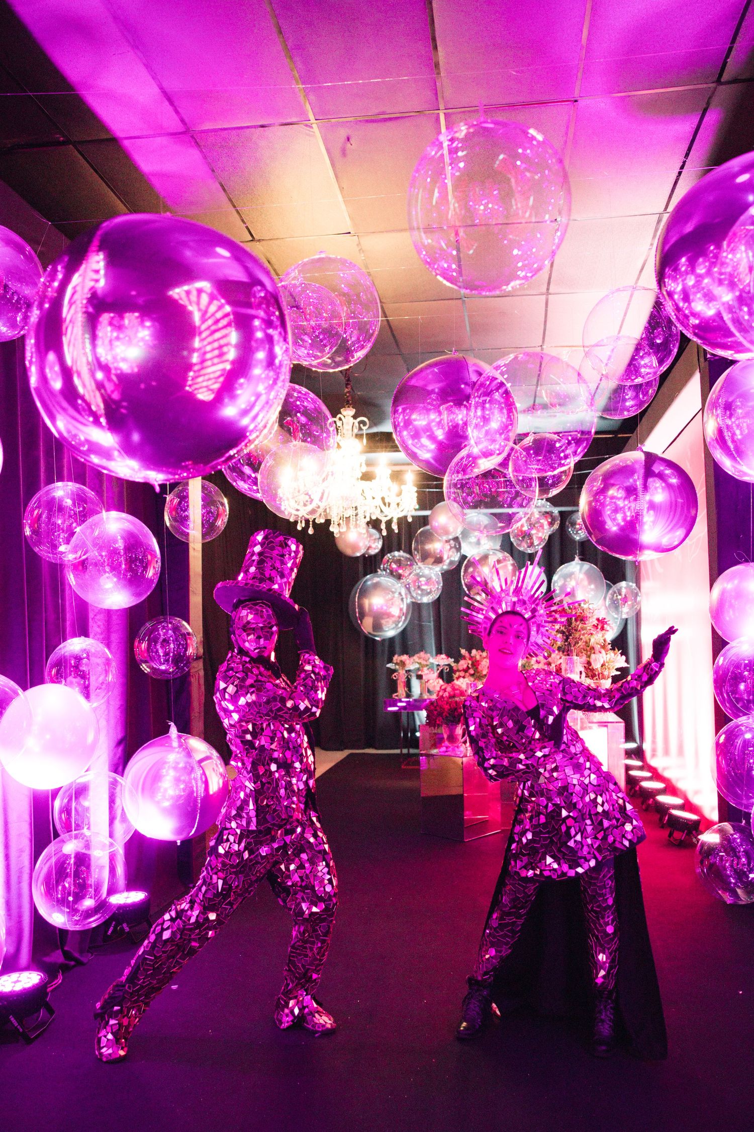 Illuminated purple party decorations featuring glowing spherical lights and metallic figures in a dark venue.