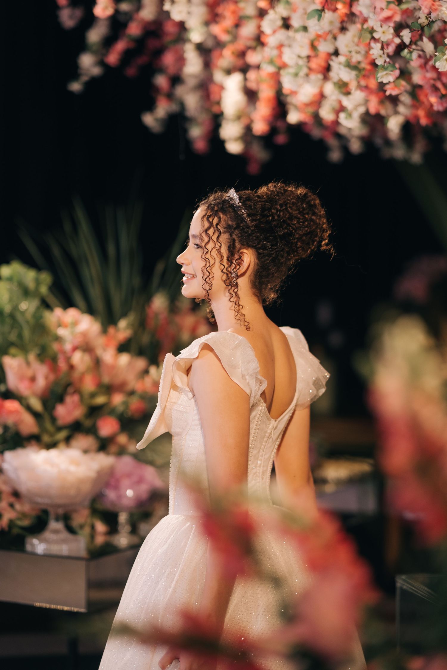 Back view of a wedding dress with delicate bow details under cascading pink floral decor.