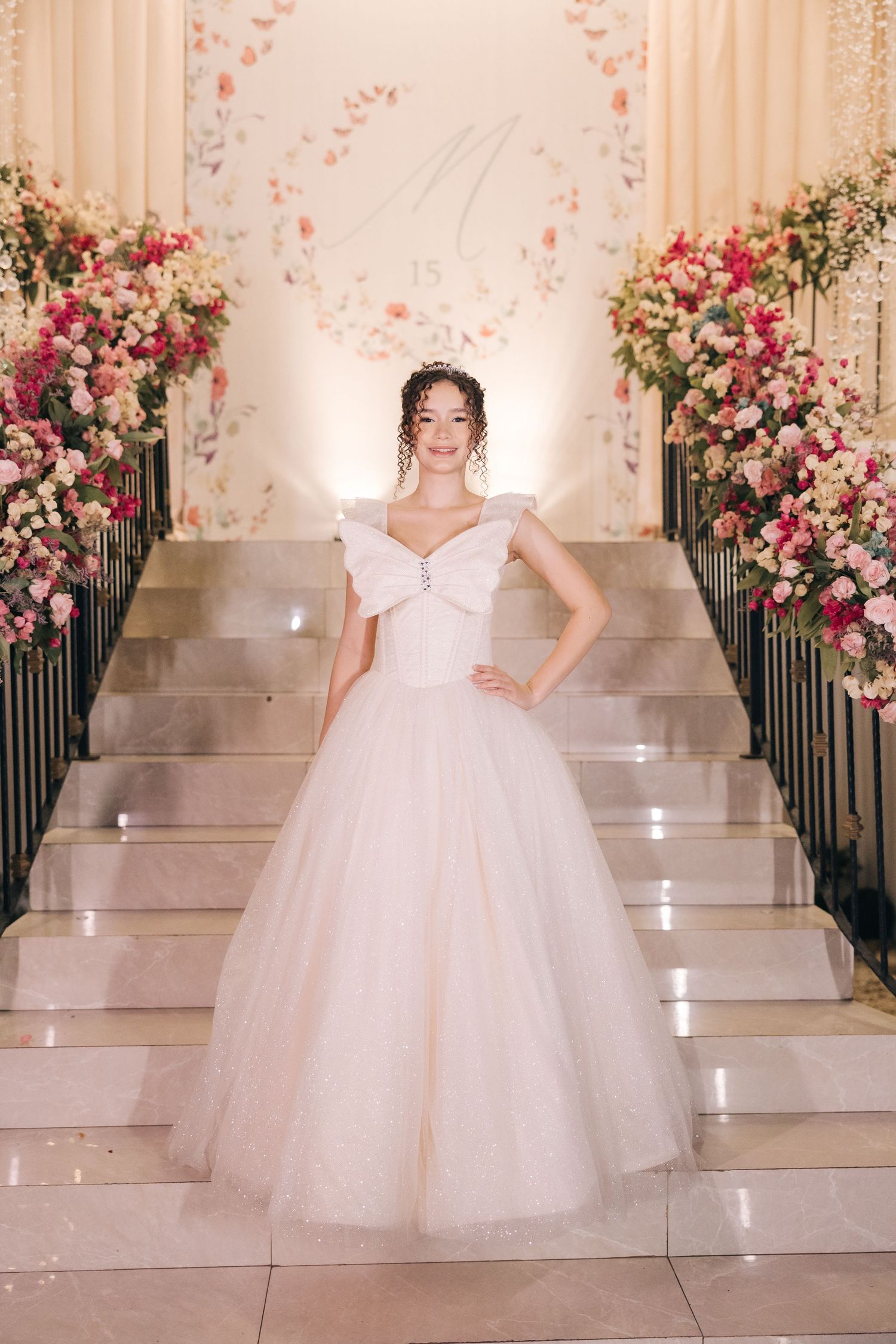 Elegant bridal portrait on grand staircase decorated with pink and peach floral arrangements.