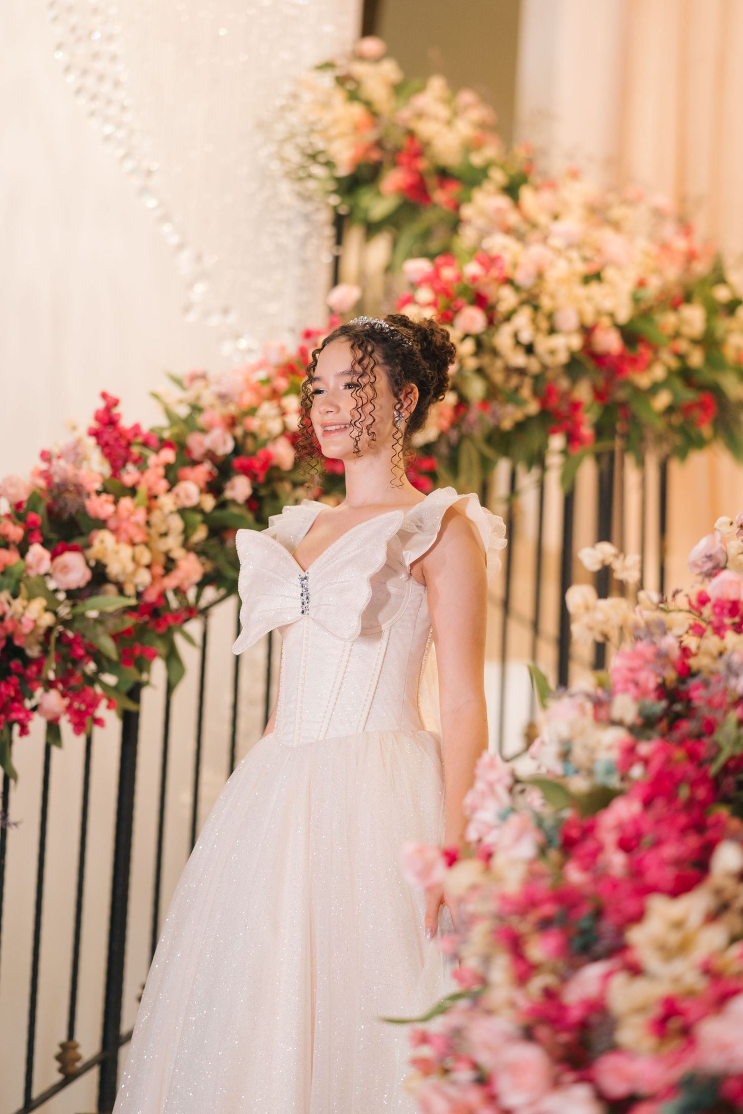 Wedding gown with structured bodice photographed against staircase adorned with pink and coral flowers.