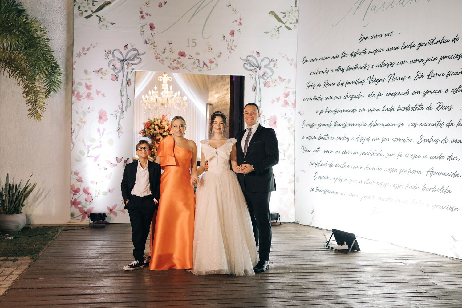 A wedding celebration in an elegant venue with floral decor and script-covered walls.