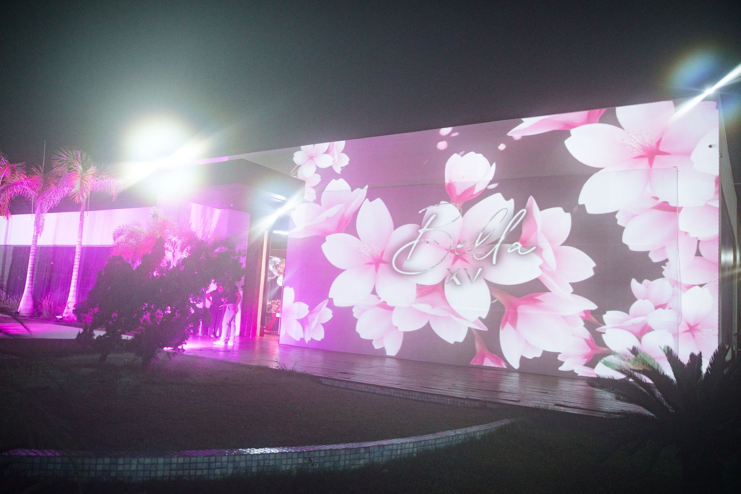 Large LED display showing cherry blossom artwork with purple ambient lighting at night event.