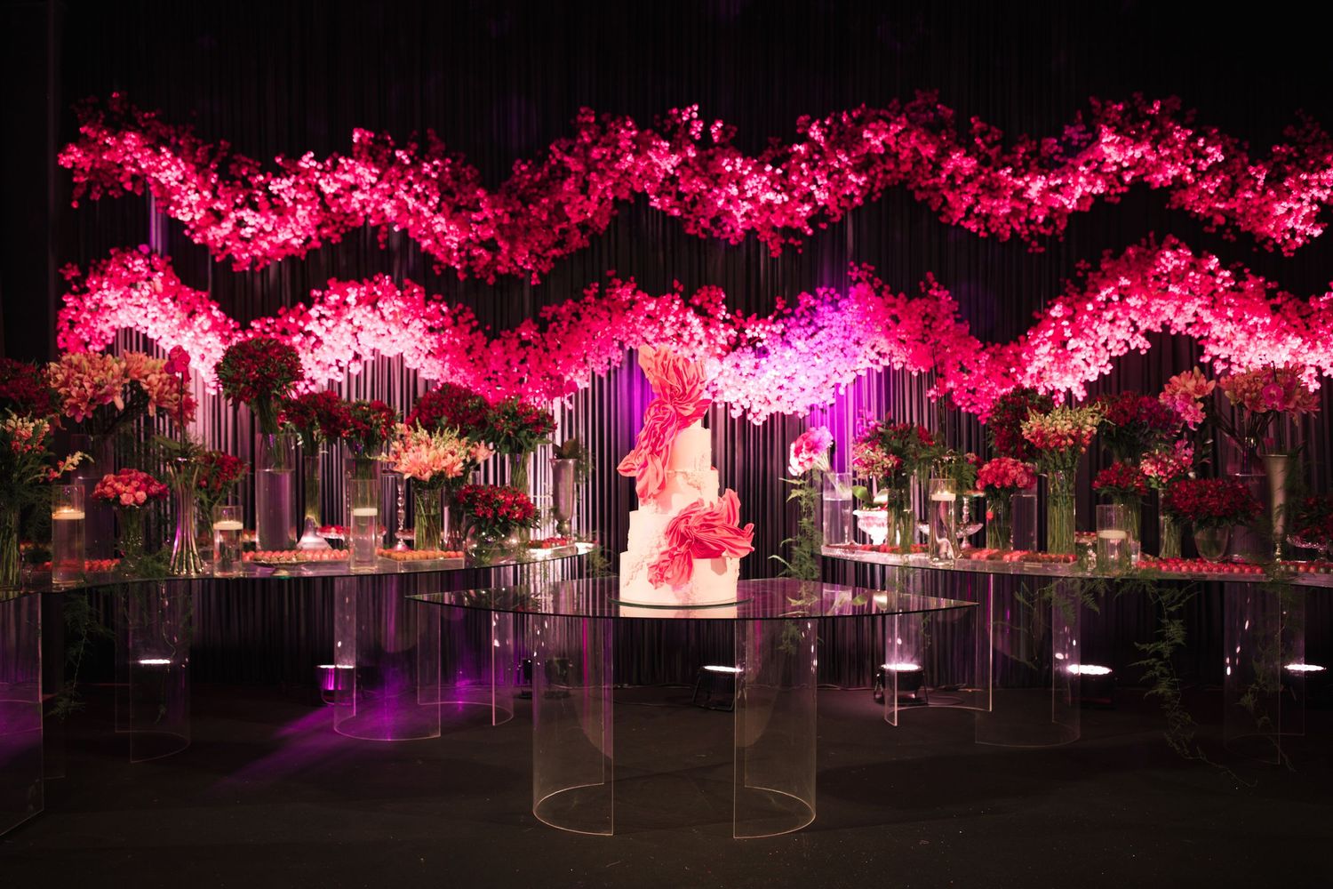 Elegant reception setup with hanging pink cherry blossoms and illuminated display pedestals.