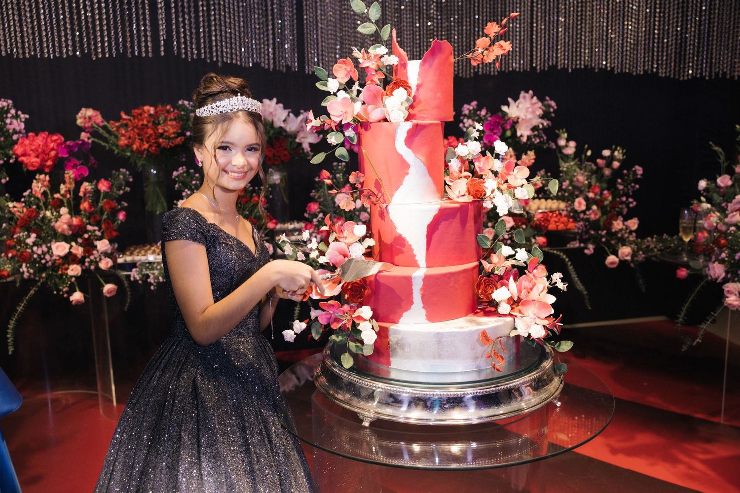 Dark evening gown and statement cake with red geometric design surrounded by coral and pink floral arrangements.