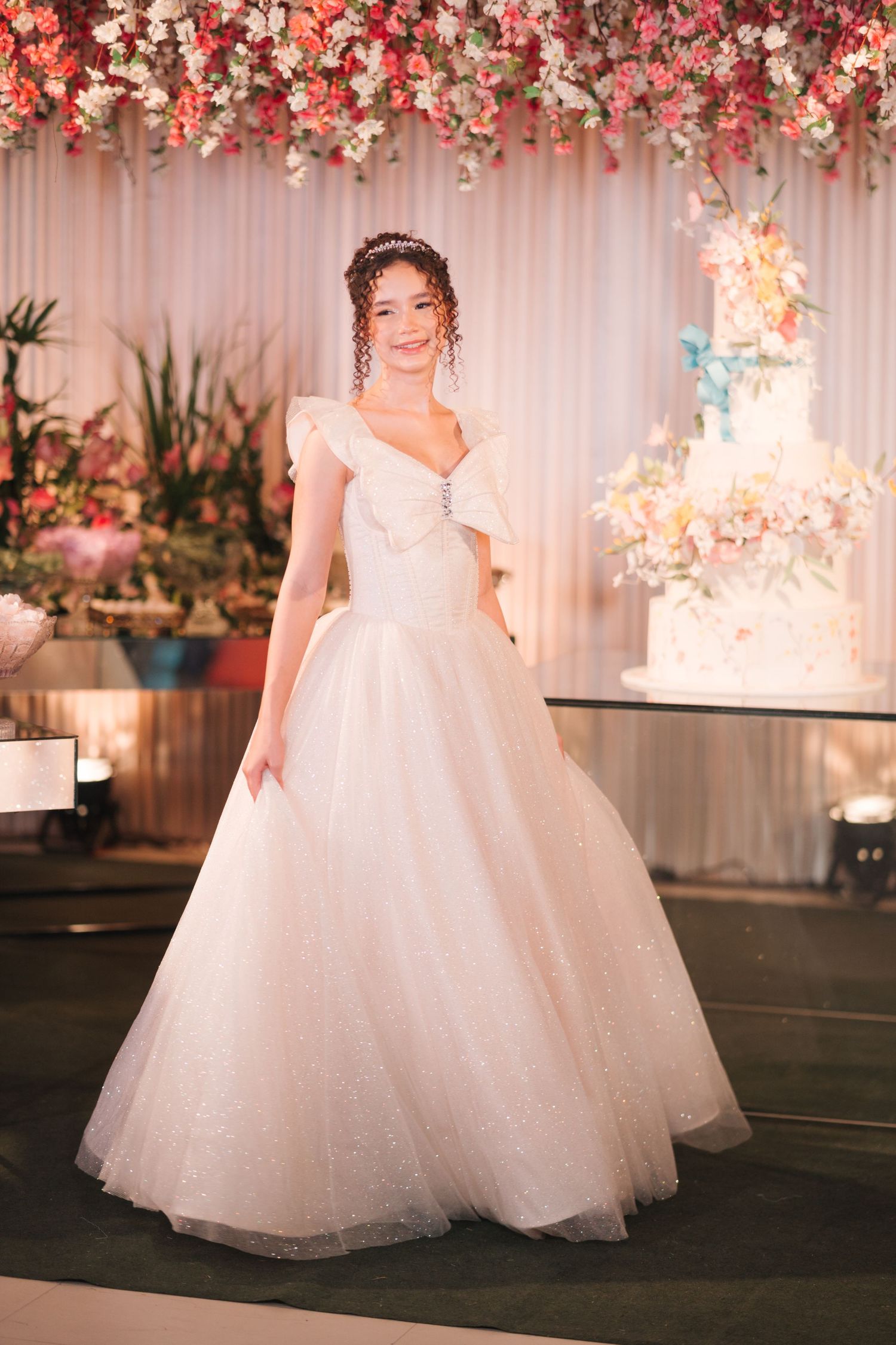 Princess-style wedding dress with tulle skirt photographed under cascading pink and white floral installation.
