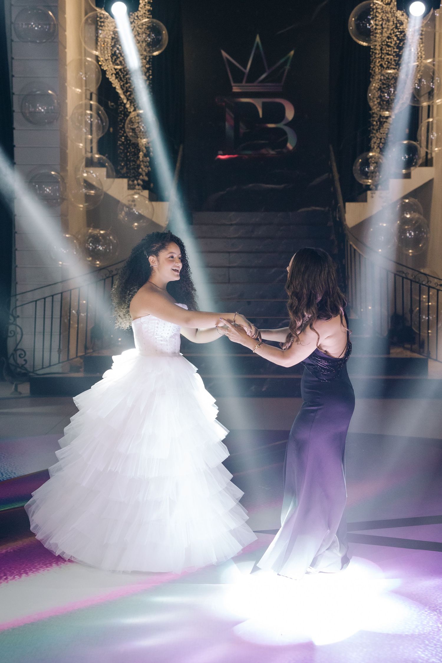 A dramatic dance scene at a celebration with two people dancing in spotlights on a decorated floor.