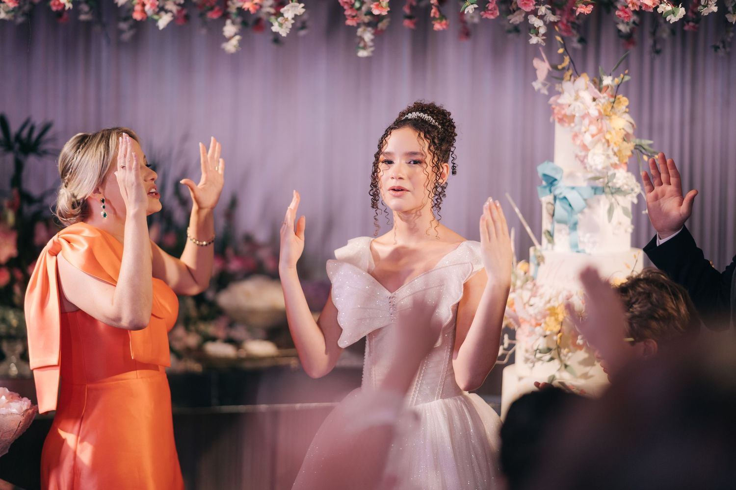 Celebration scene with raised hands and dancing in formal attire at an elegant event.