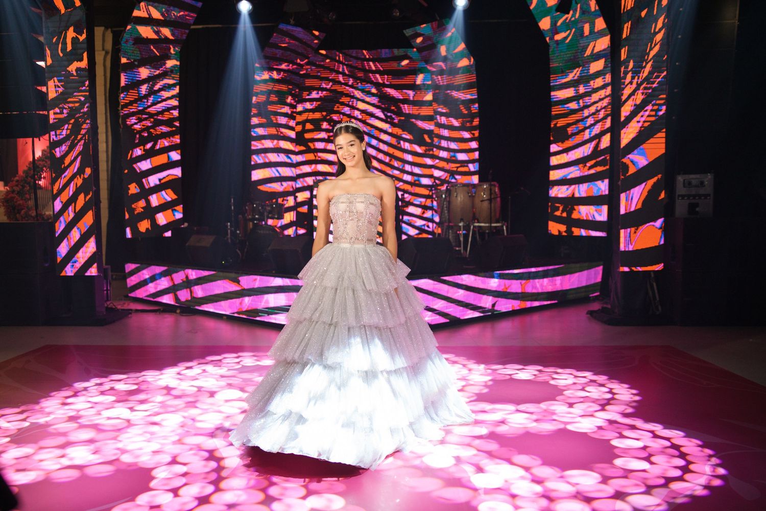 An elegant ball gown silhouette captured on a stage with dramatic lighting and digital wave patterns.