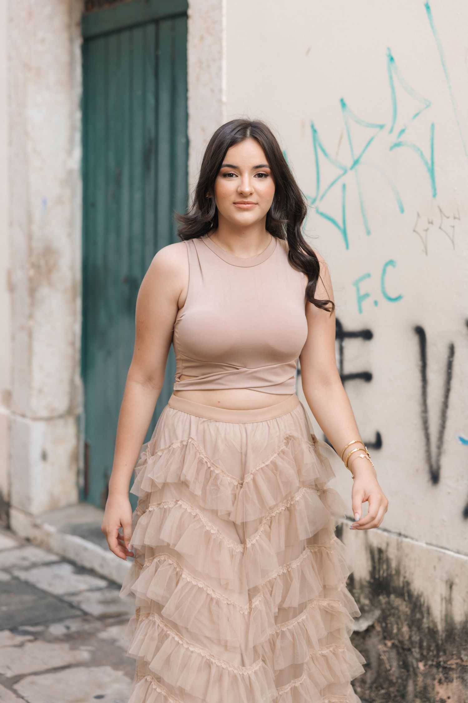 A fashionable beige outfit with ruffled tulle skirt photographed against an urban wall with graffiti.