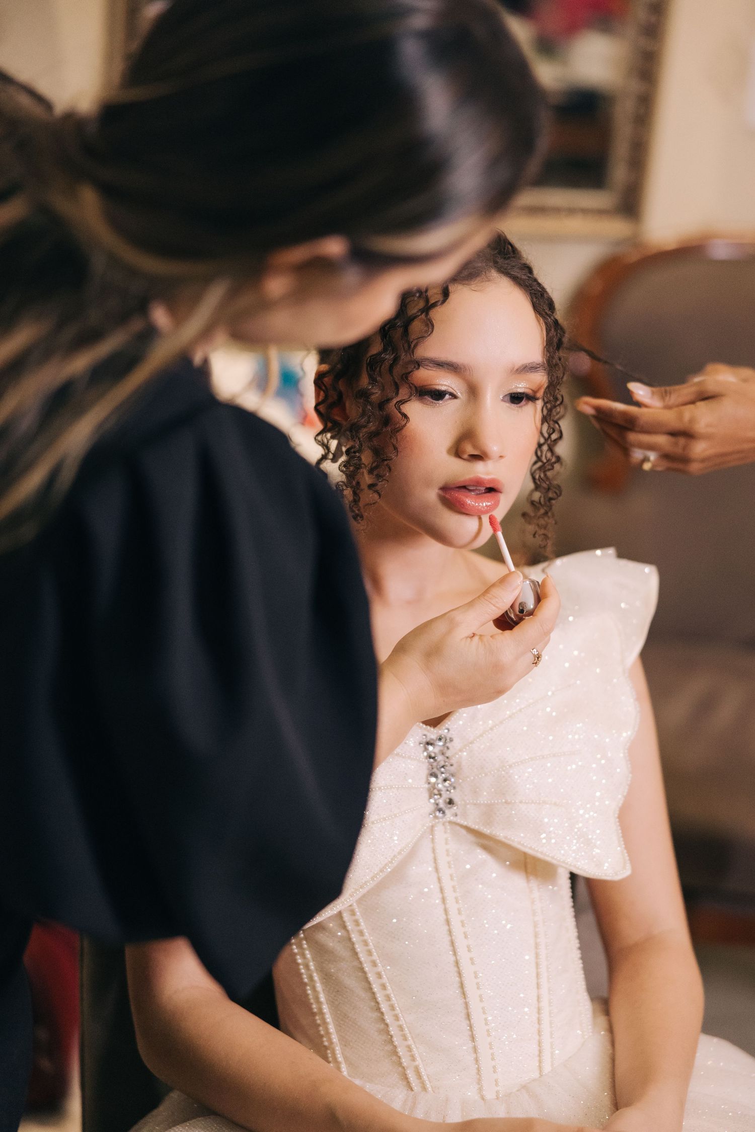 Close-up of bridal makeup application with focus on applying red lipstick.