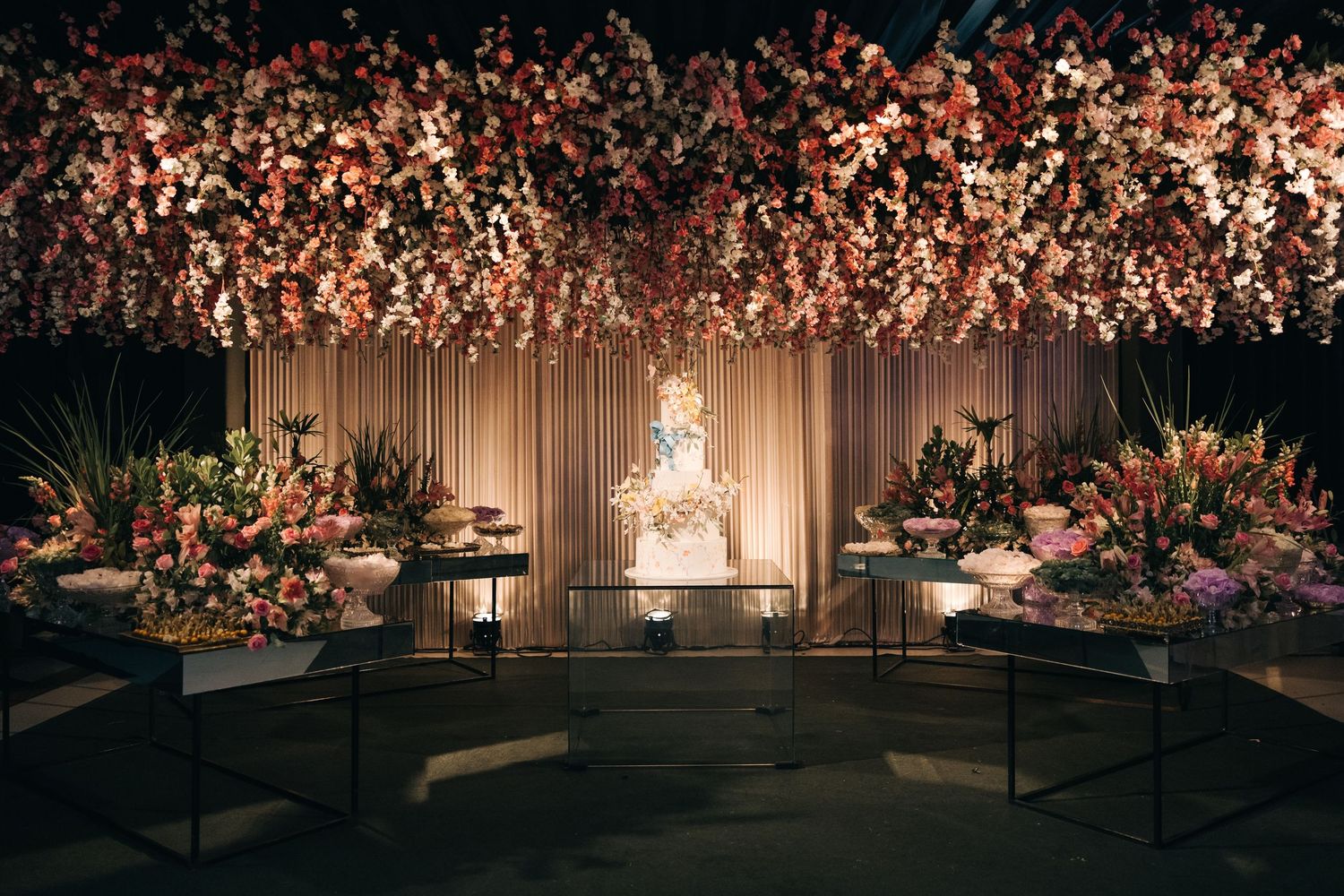 An opulent wedding stage design with cascading cherry blossoms and romantic lighting creates a dreamy atmosphere.