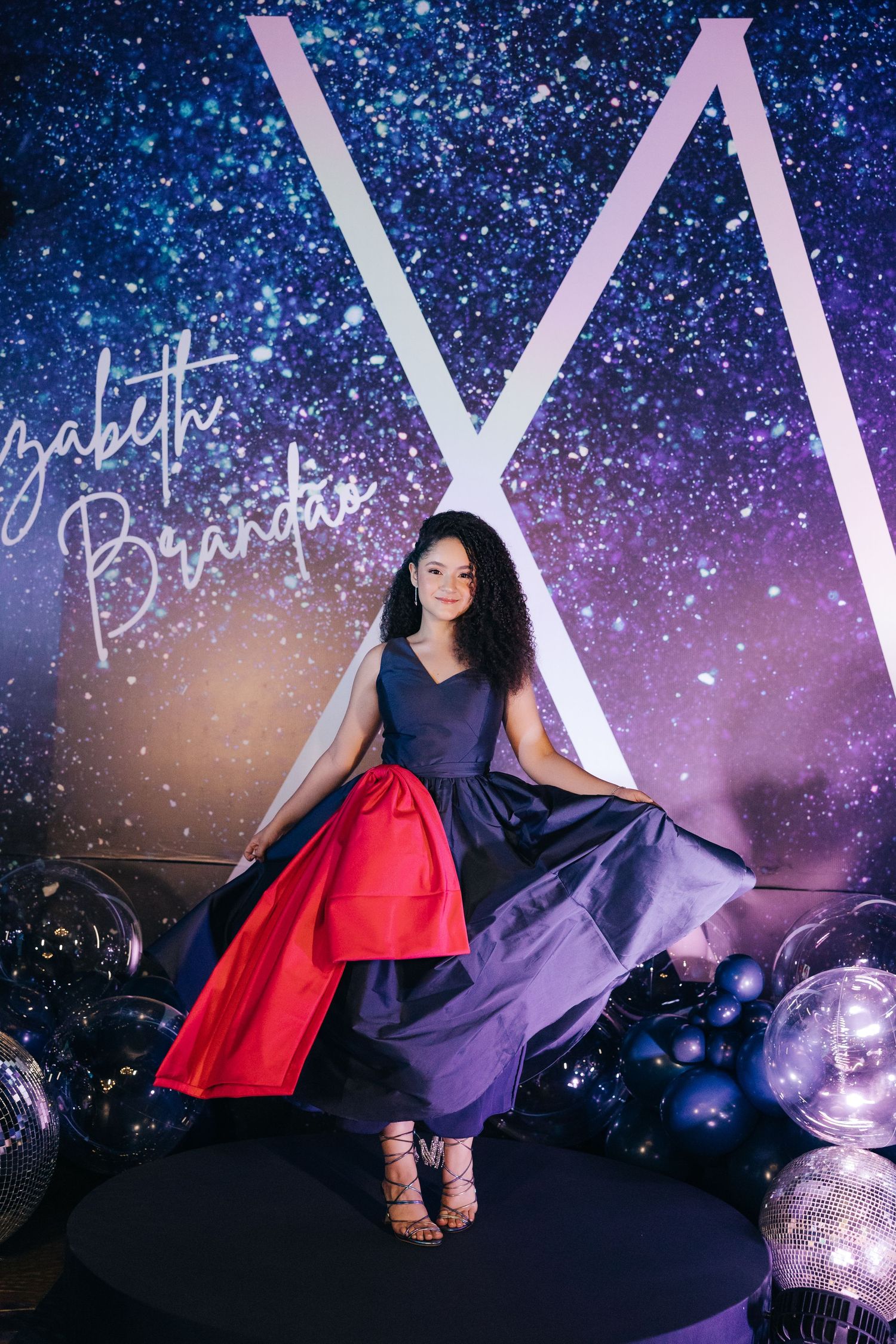 A whimsical photo against a sparkly galaxy backdrop with a flowing navy and red dress.