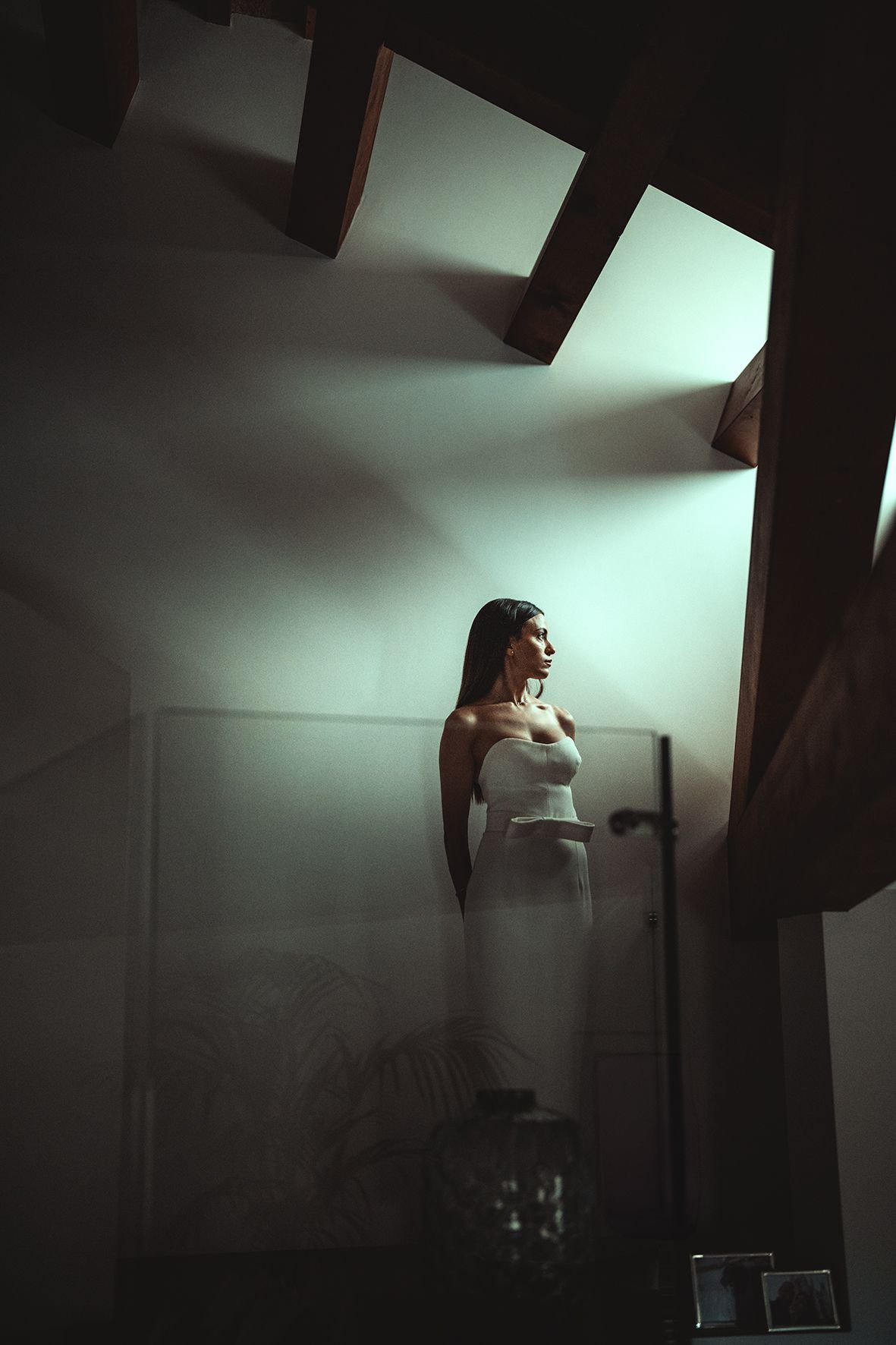 A dramatic low-angle shot shows a person in a white dress standing in dark moody lighting with geometric shadows.