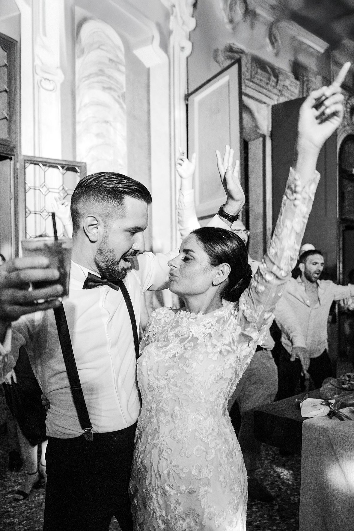 Black and white photo of newlyweds dancing and celebrating at an elegant wedding reception venue.
