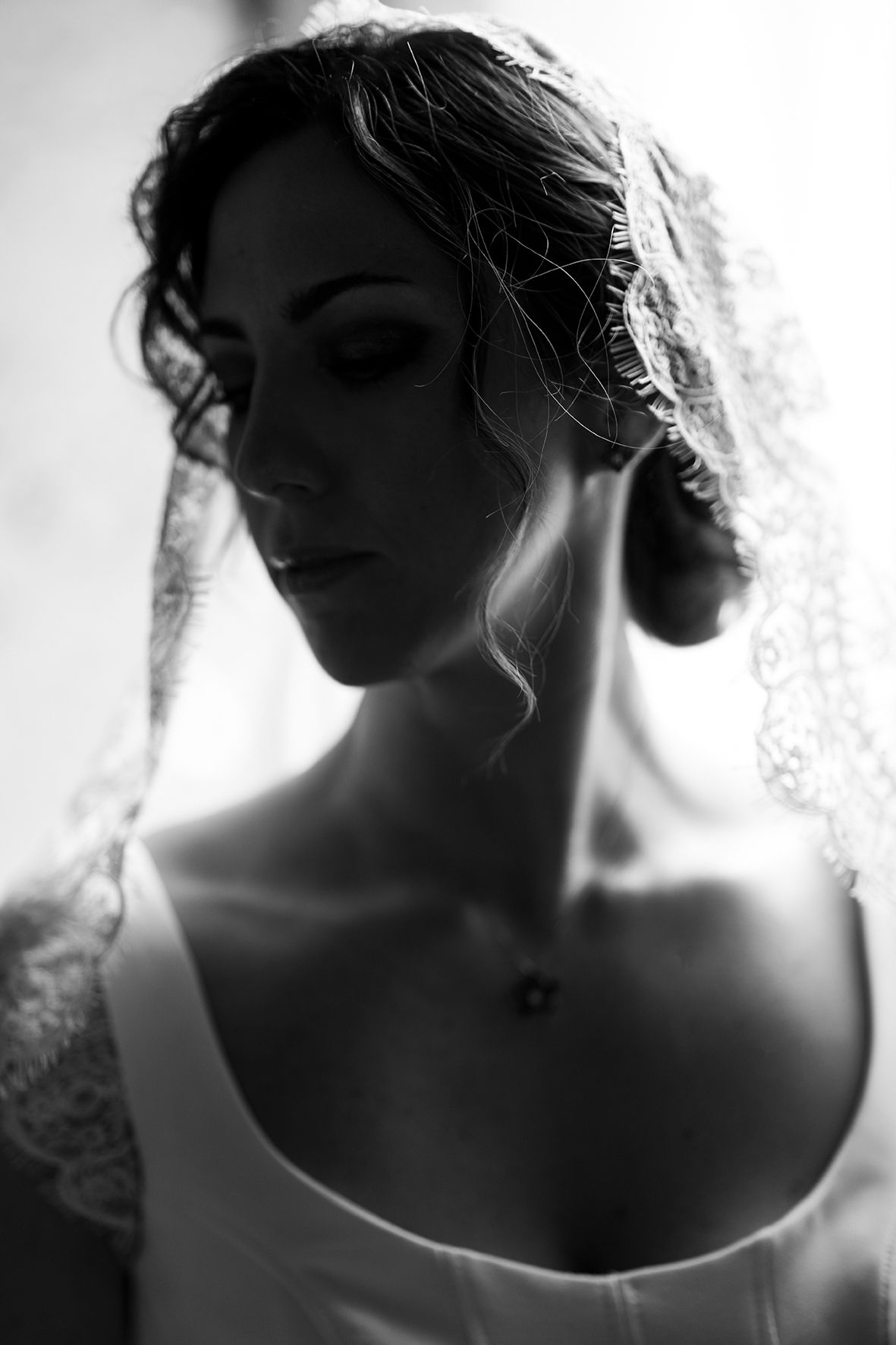Black and white artistic portrait featuring dramatic lighting, delicate veil details, and elegant bridal attire.