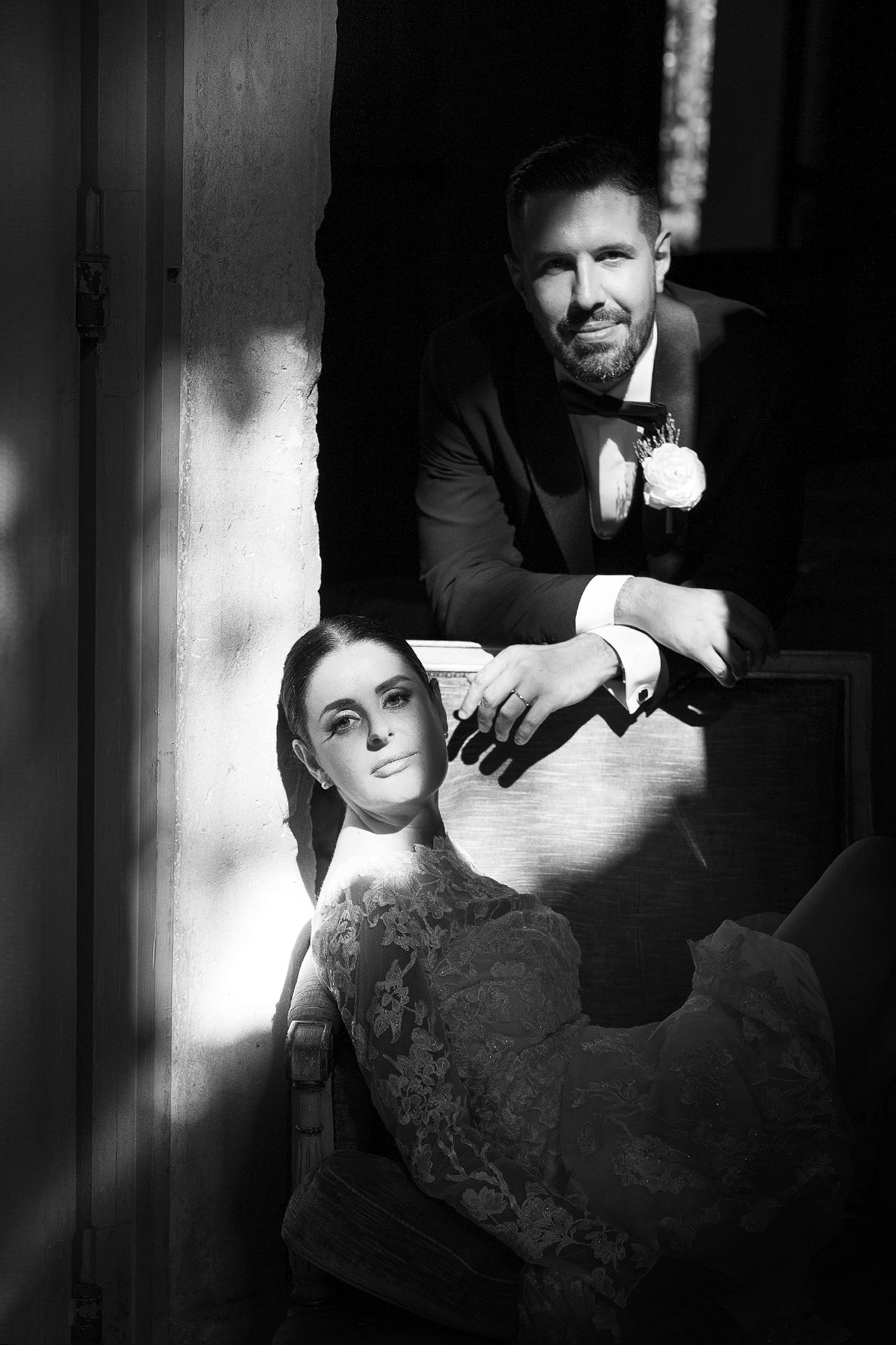 Dramatic black and white portrait of a couple in formal attire with contrasting lighting effects.