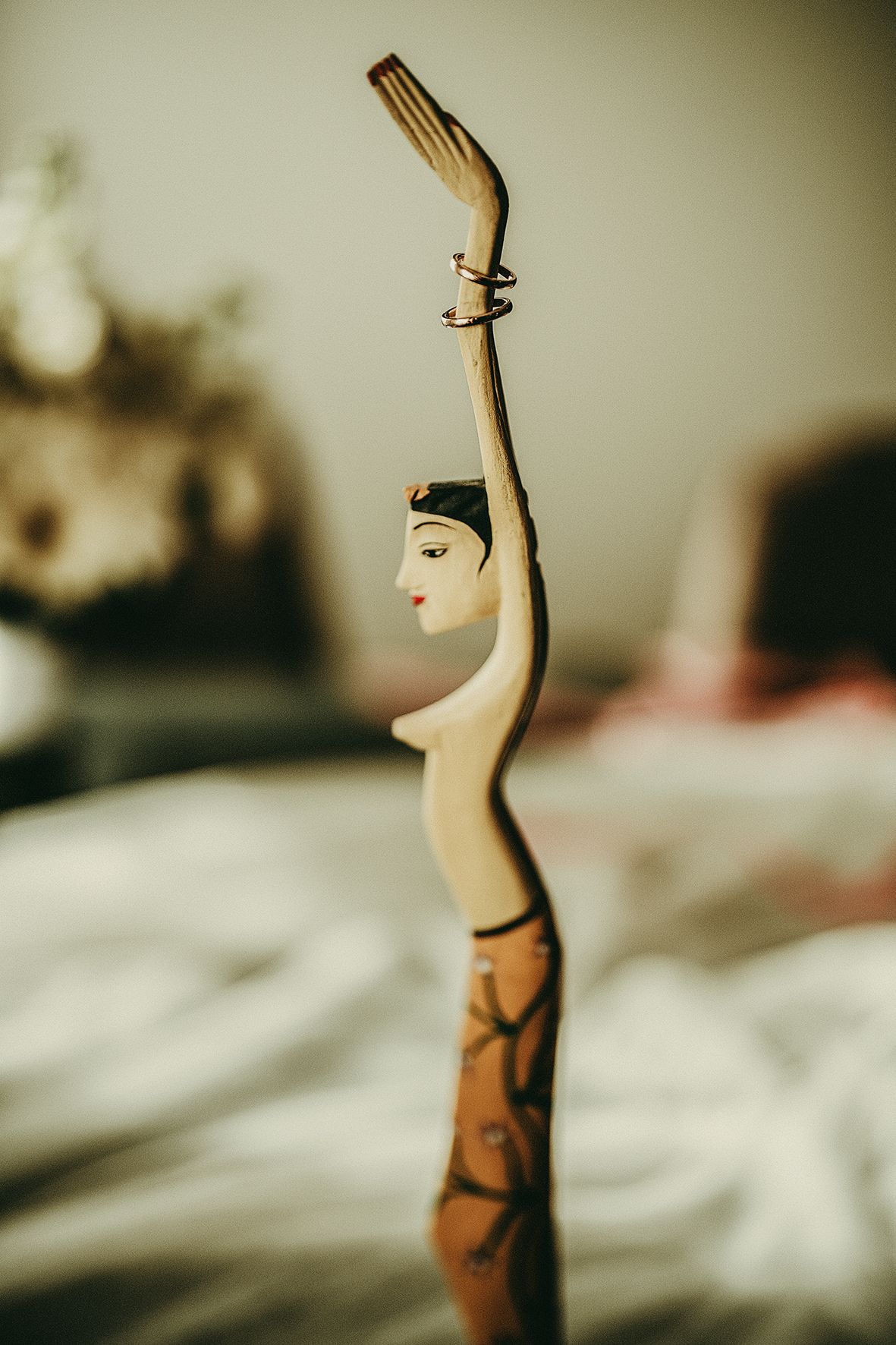 A vintage carved wooden figurine of an elegant female dancer with delicate painted features and a graceful pose against a soft background.