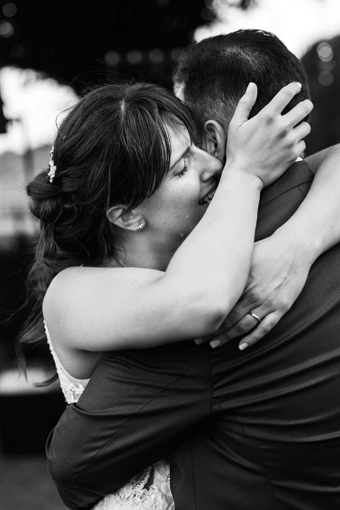 Black and white photo of tender emotional embrace between a bride and groom during their wedding celebration.