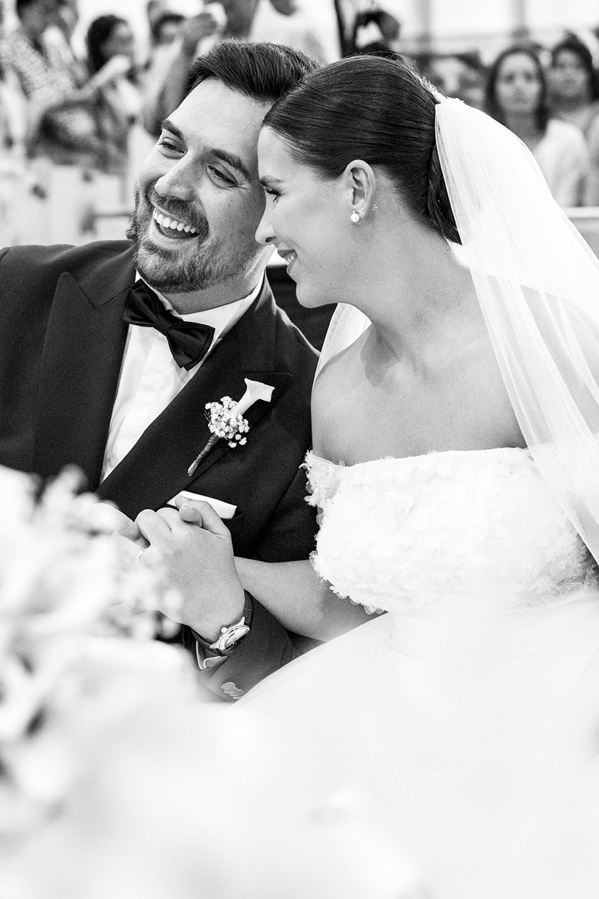 Black and white candid photograph of a joyful bride and groom sharing a tender moment during their wedding ceremony.