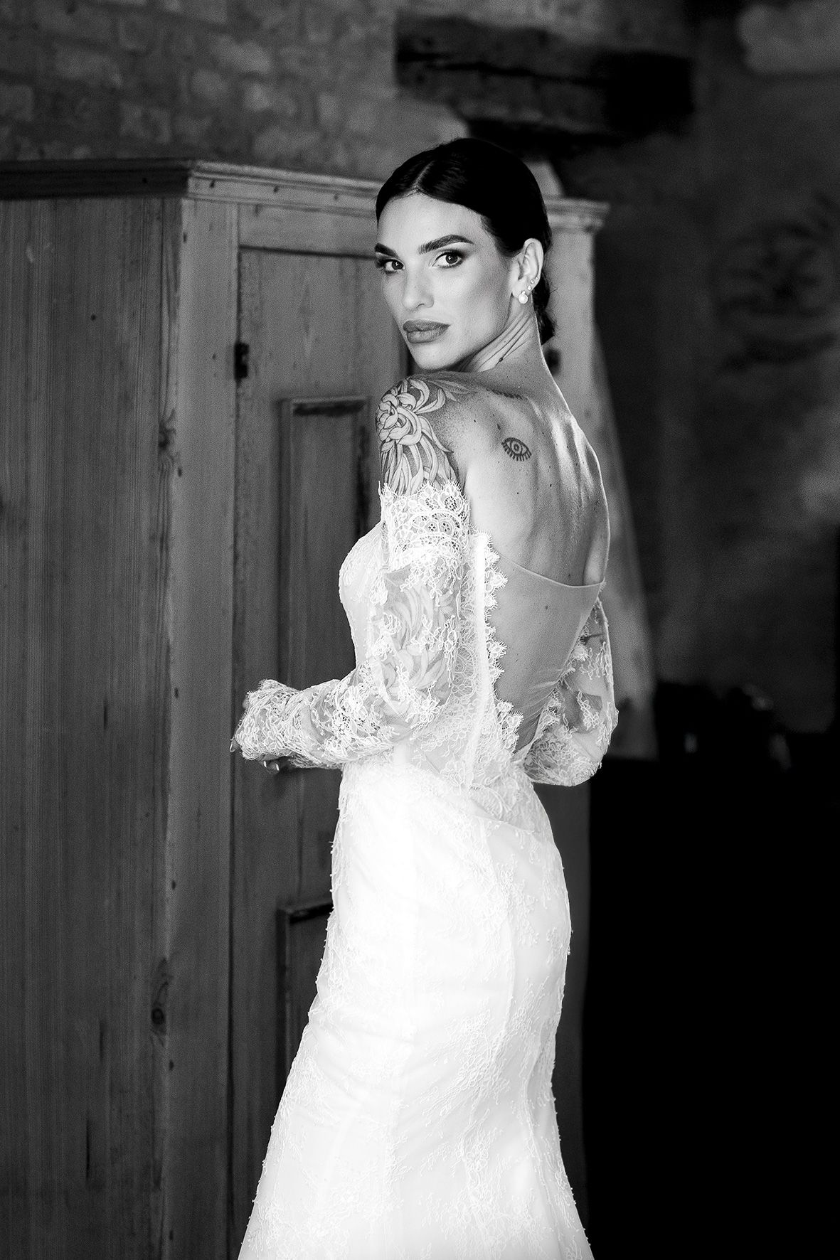 Black and white portrait of a bride in detailed lace wedding dress with open back design.
