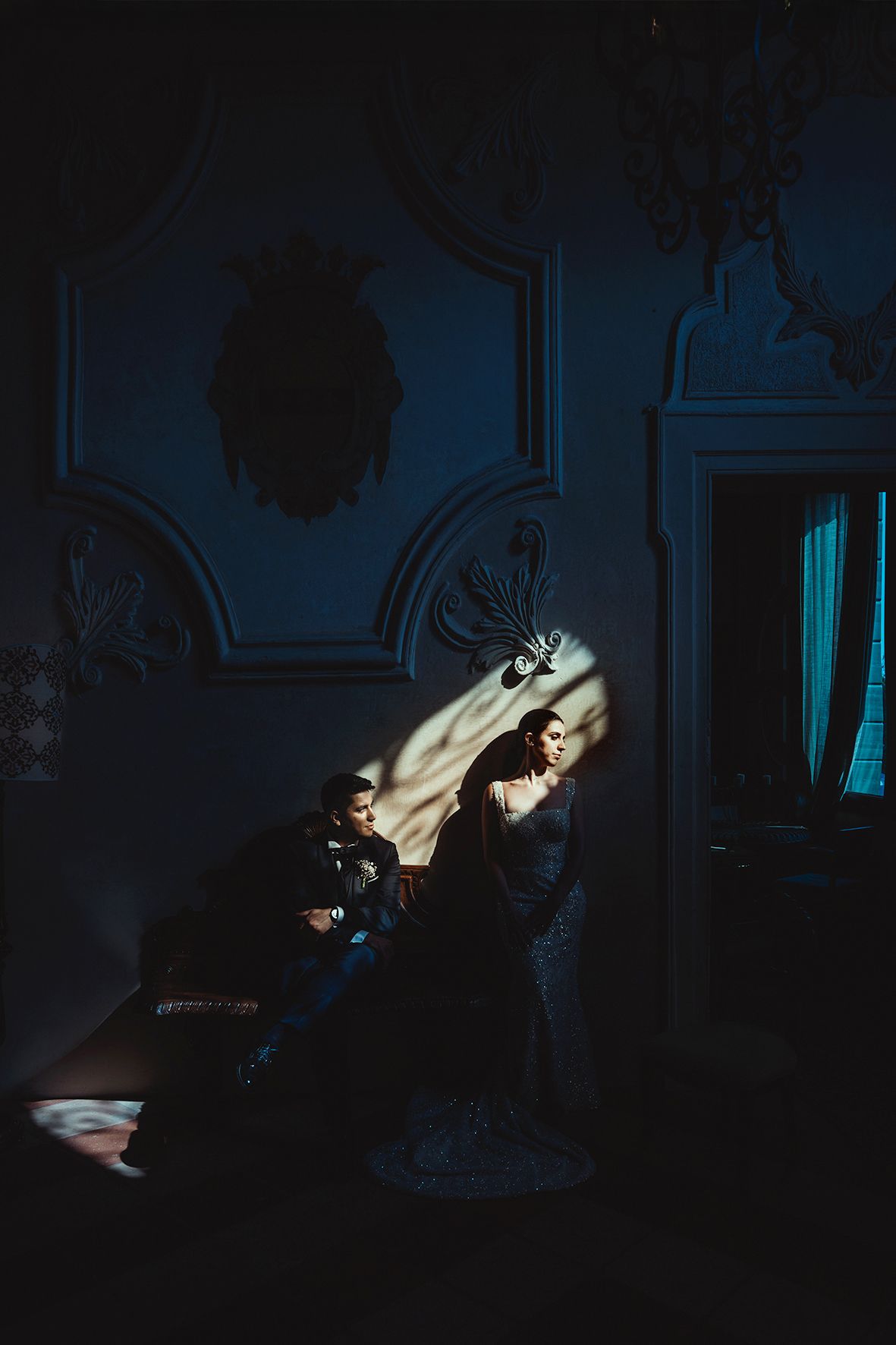 A dramatic shadow scene in a dimly lit vintage room with ornate wall decor and a spotlight casting dramatic shadows.