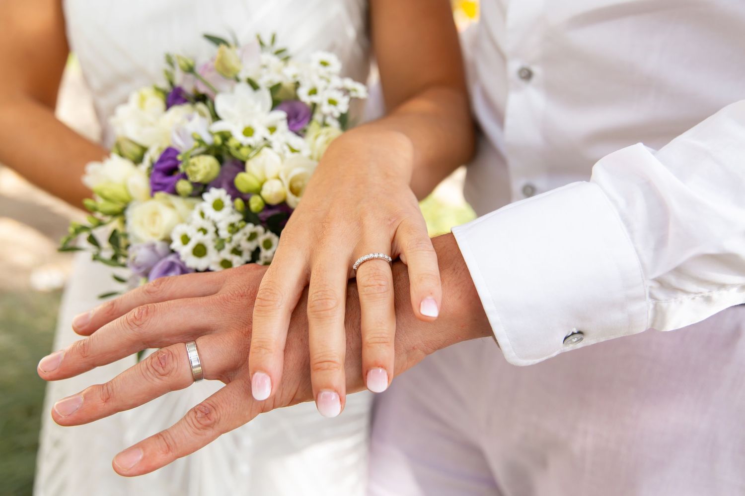 Photo des mains des mariés portant leurs alliances, détail symbolique capturé après la cérémonie de mariage civil ou religieux.