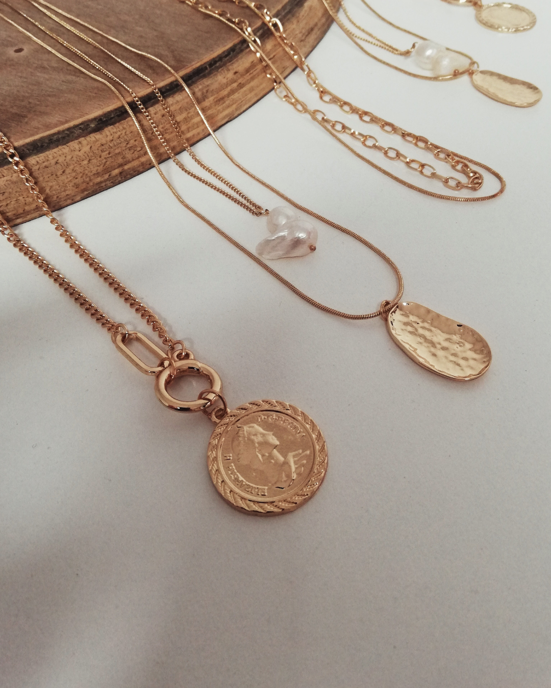 Photo en packshot de colliers, mise en valeur des détails et du design sur fond neutre et lumineux. Bijoux.
