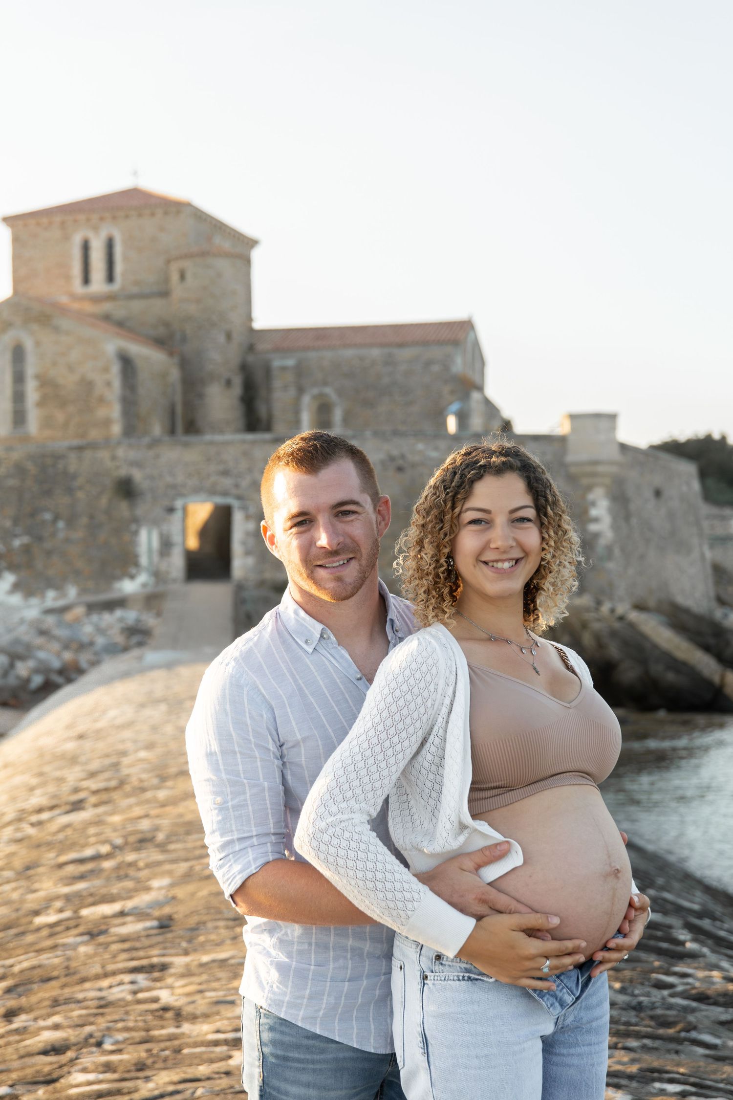 Portrait de couple en attendant bébé, lumière naturelle et tendresse.