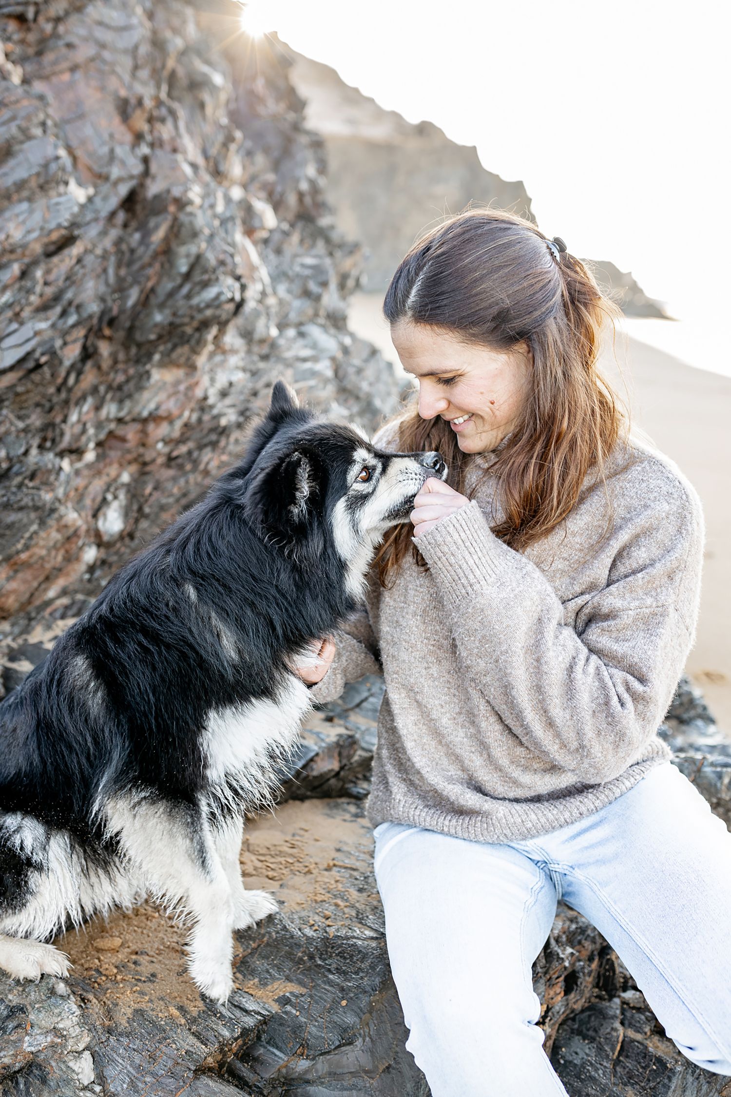 Photo d’une femme avec son chien sur la plage, moment joyeux et détendu capturé sous le soleil.