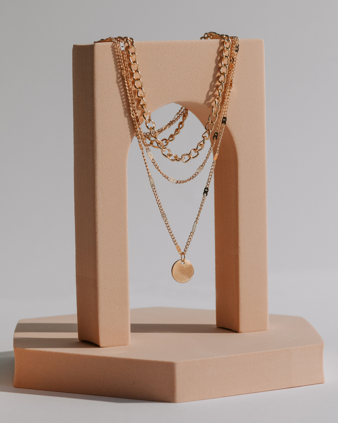 Photo en packshot de colliers, mise en valeur des détails et du design sur fond neutre et lumineux. Bijoux.