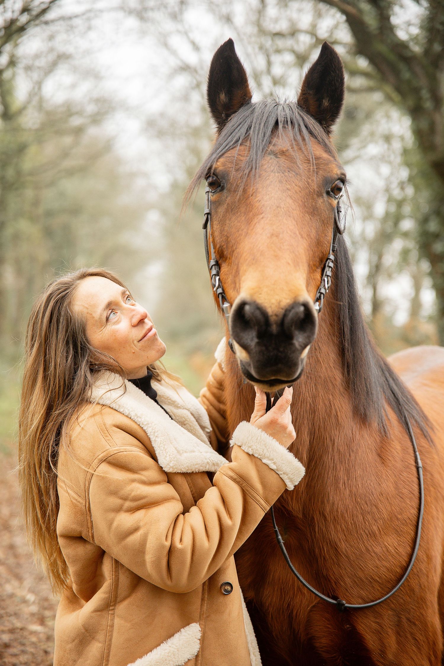Photo d’une femme en compagnie de son cheval, moment de complicité et de sérénité capturé en extérieur.
