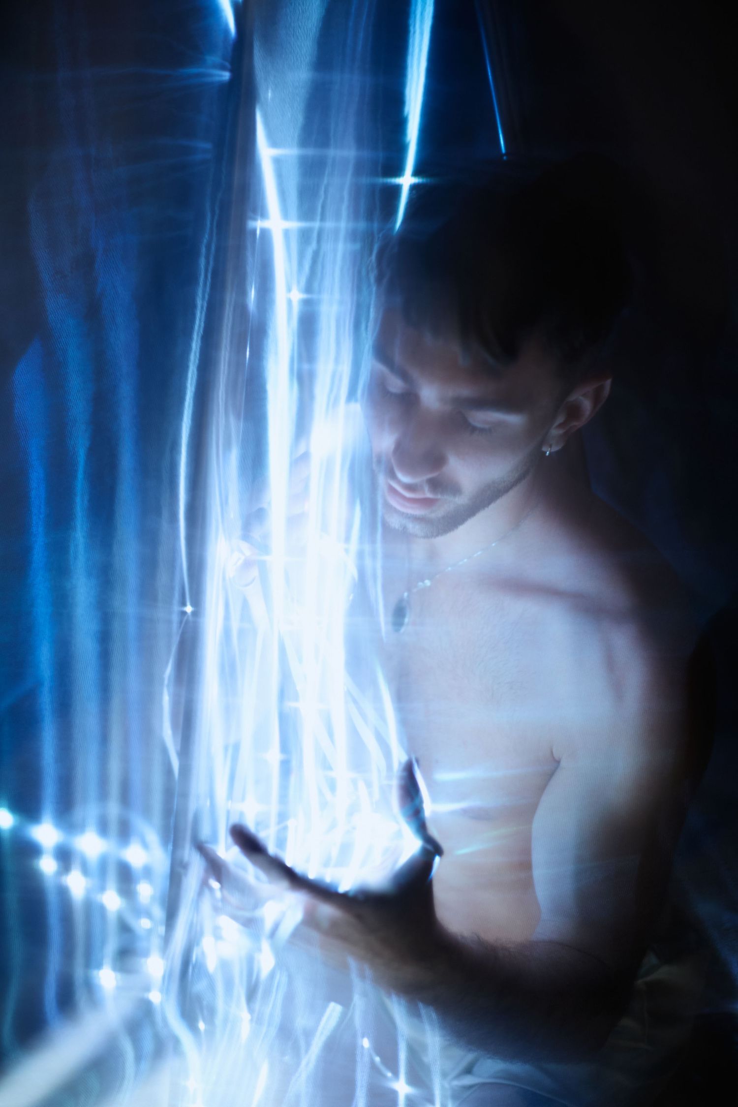 Abstract portrait style images with blue streaks of light creating an ethereal, moody atmosphere in low light conditions.