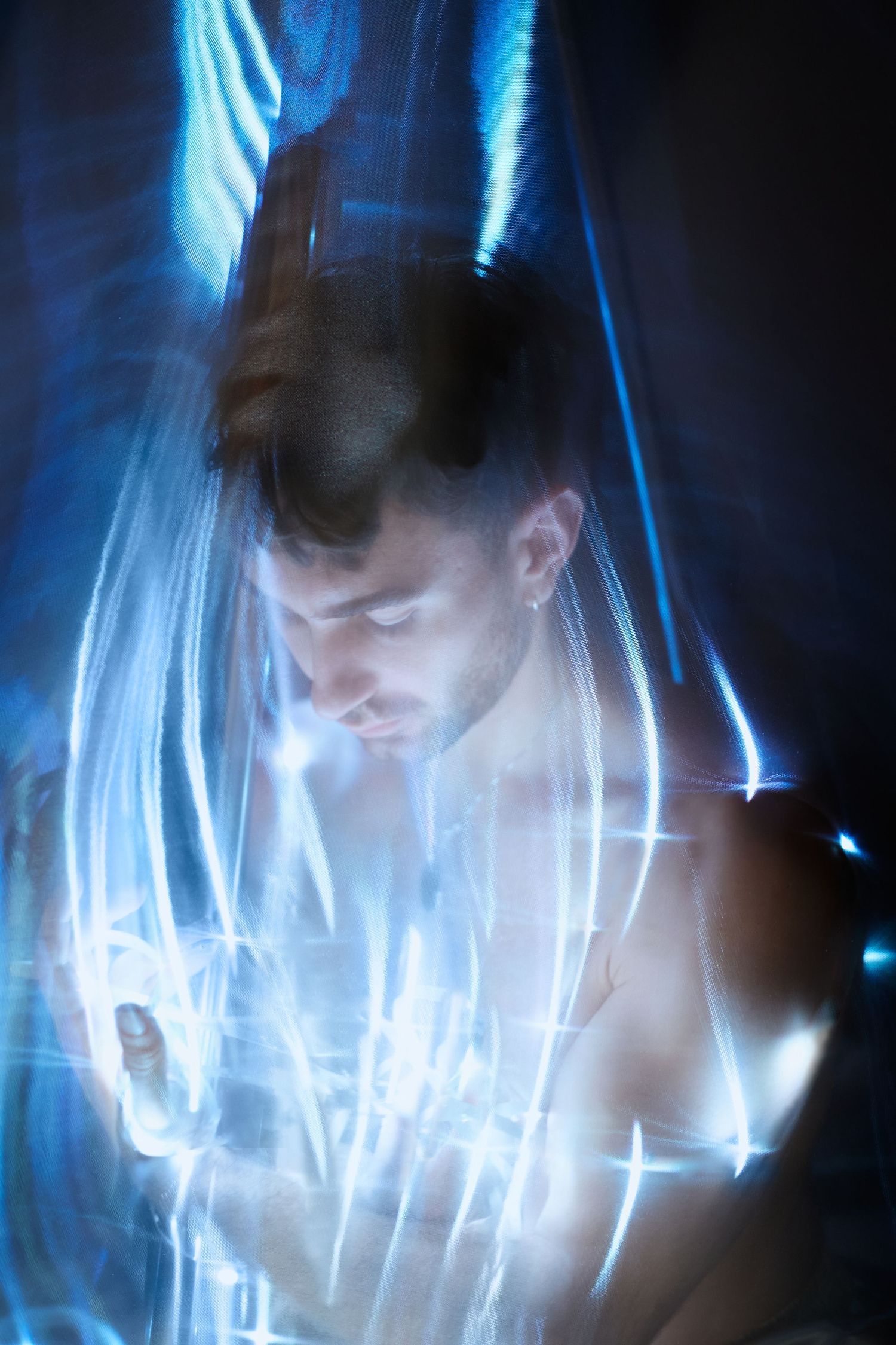 Abstract artistic portrait with blue light streaks creating an ethereal motion blur effect in darkness.