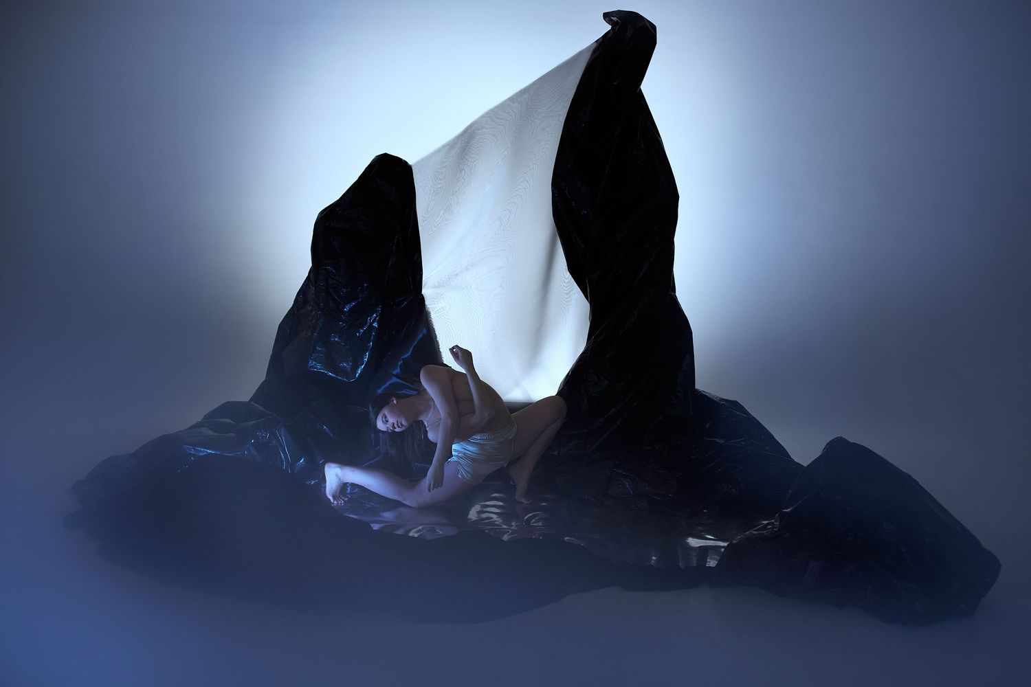 A dark silhouetted rocky mountain peak illuminated by ethereal blue backlighting creating a mystical atmosphere.