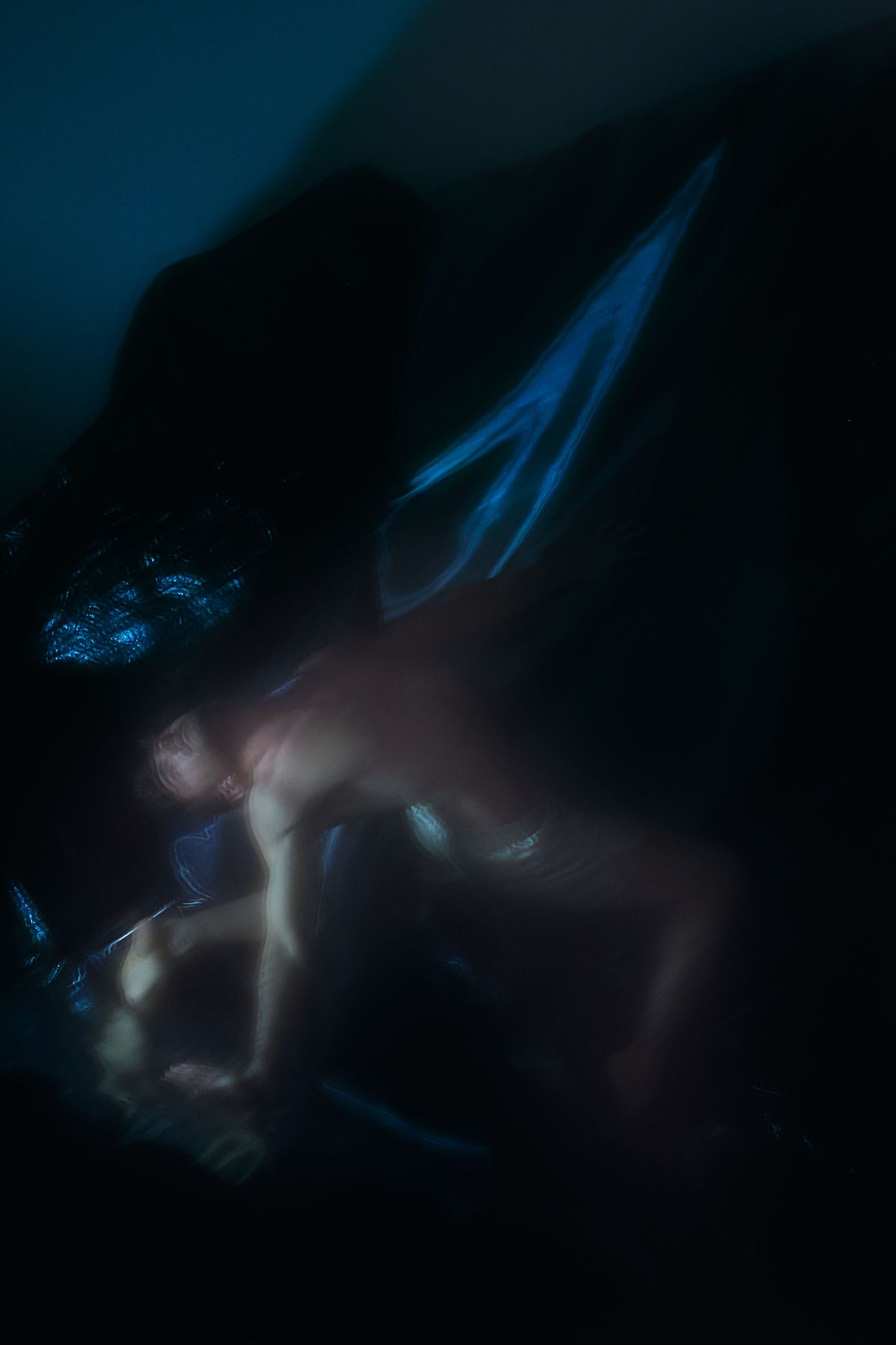 A series of abstract blurred images in dark blue and black tones with ethereal light streaks creating a moody atmosphere.