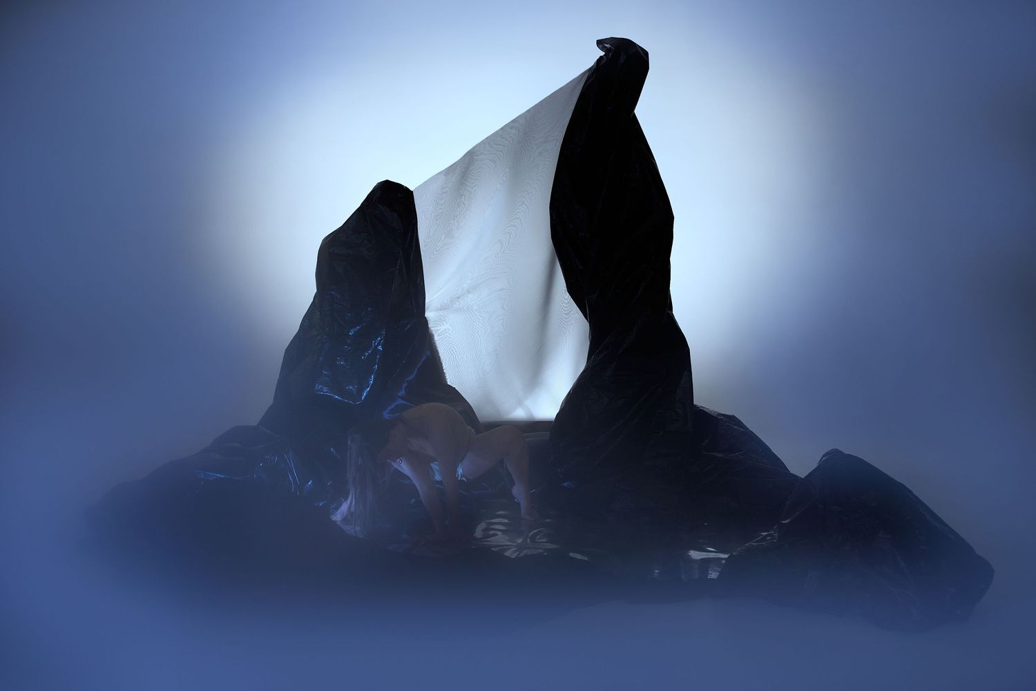 Dark jagged mountain peaks silhouetted against a misty blue backlit sky.