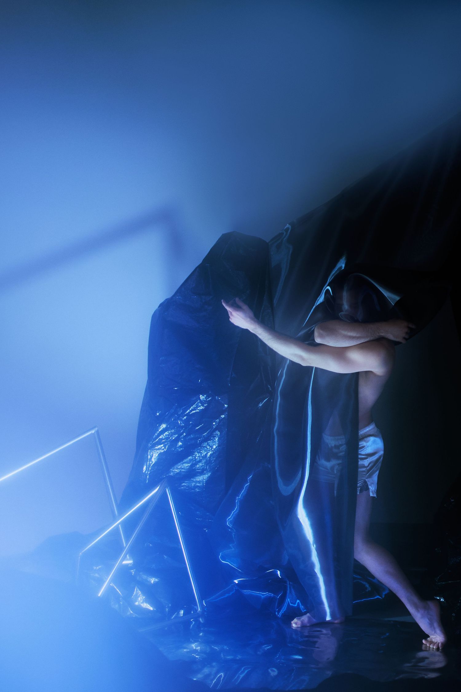 Artistic performance with a person in blue light against a dark background creating a dramatic silhouette effect.