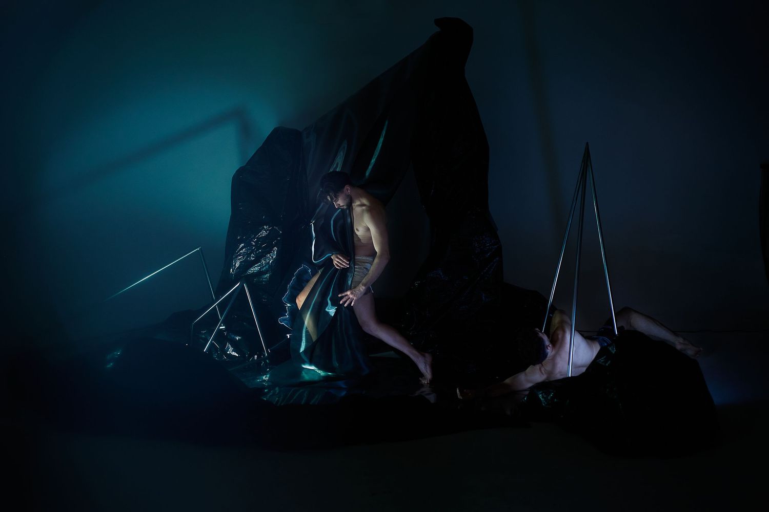 A group of underwater cave divers explore dark caverns with bright diving lights illuminating their path.