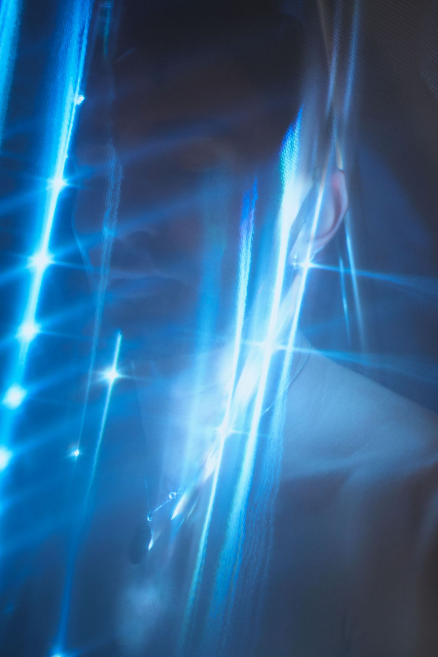 Abstract blue light streaks and sparkles create an ethereal effect against a dark background.