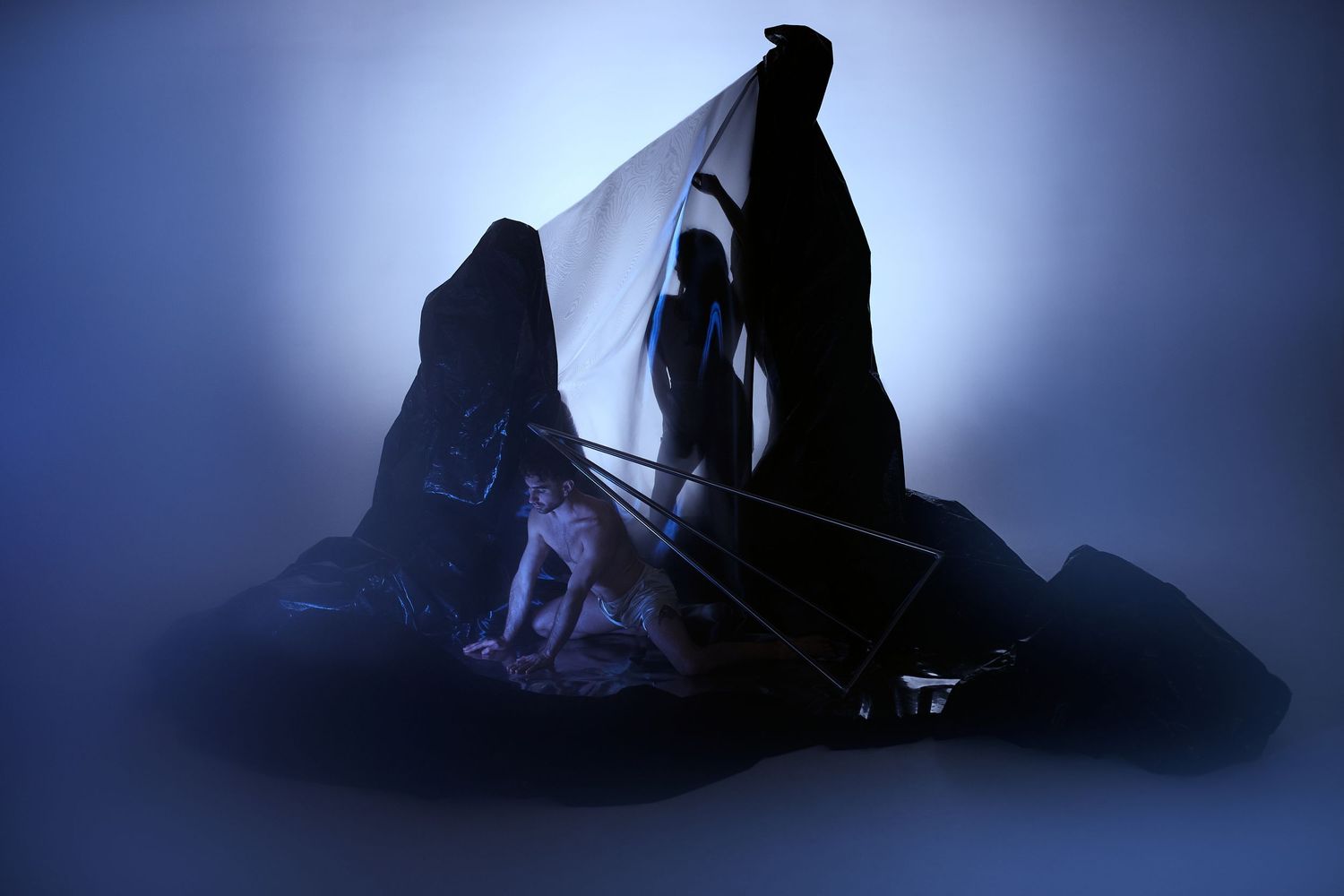 Two figures draped in dark cloaks face each other in a dramatic silhouette against a misty blue background.