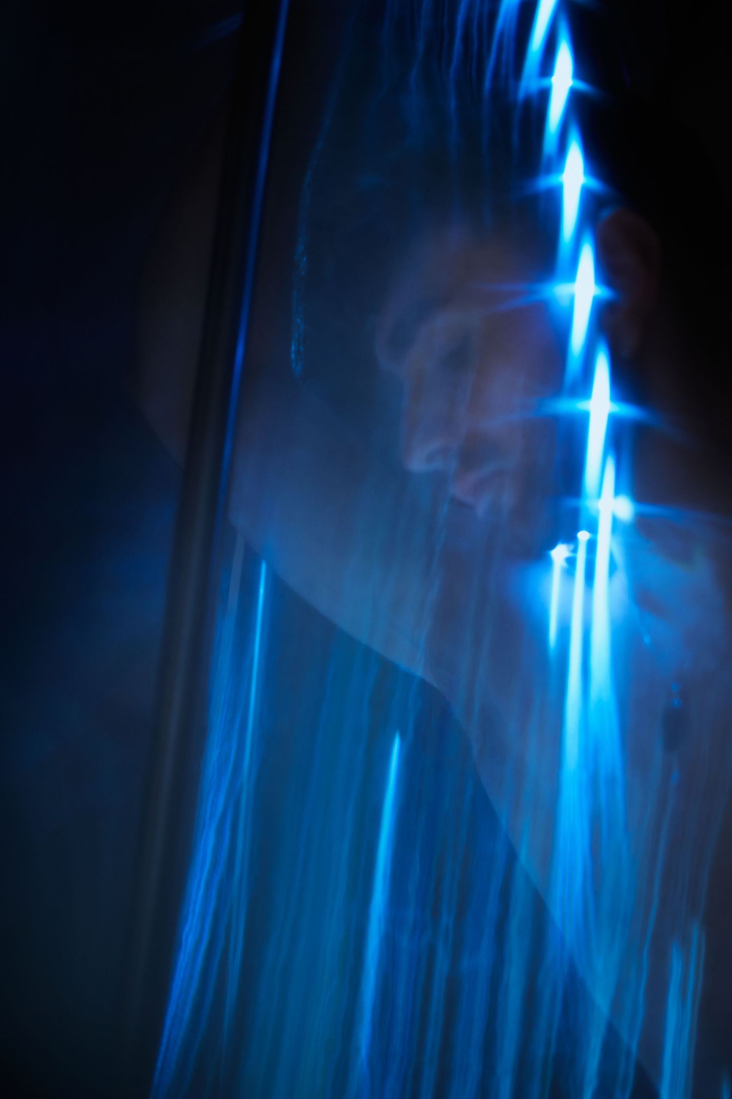 Abstract blue light streaks against black background create ethereal glowing patterns in long exposure photography.