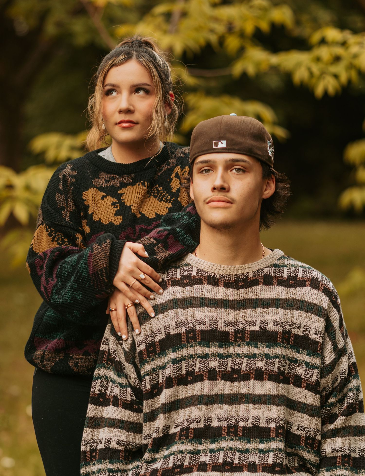 A casual fall portrait session showing someone in a striped sweater against blurred autumn foliage.