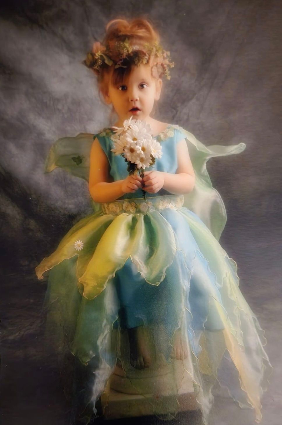 Dreamy portrait in a fairy costume with ethereal blue-green tulle and flowers.