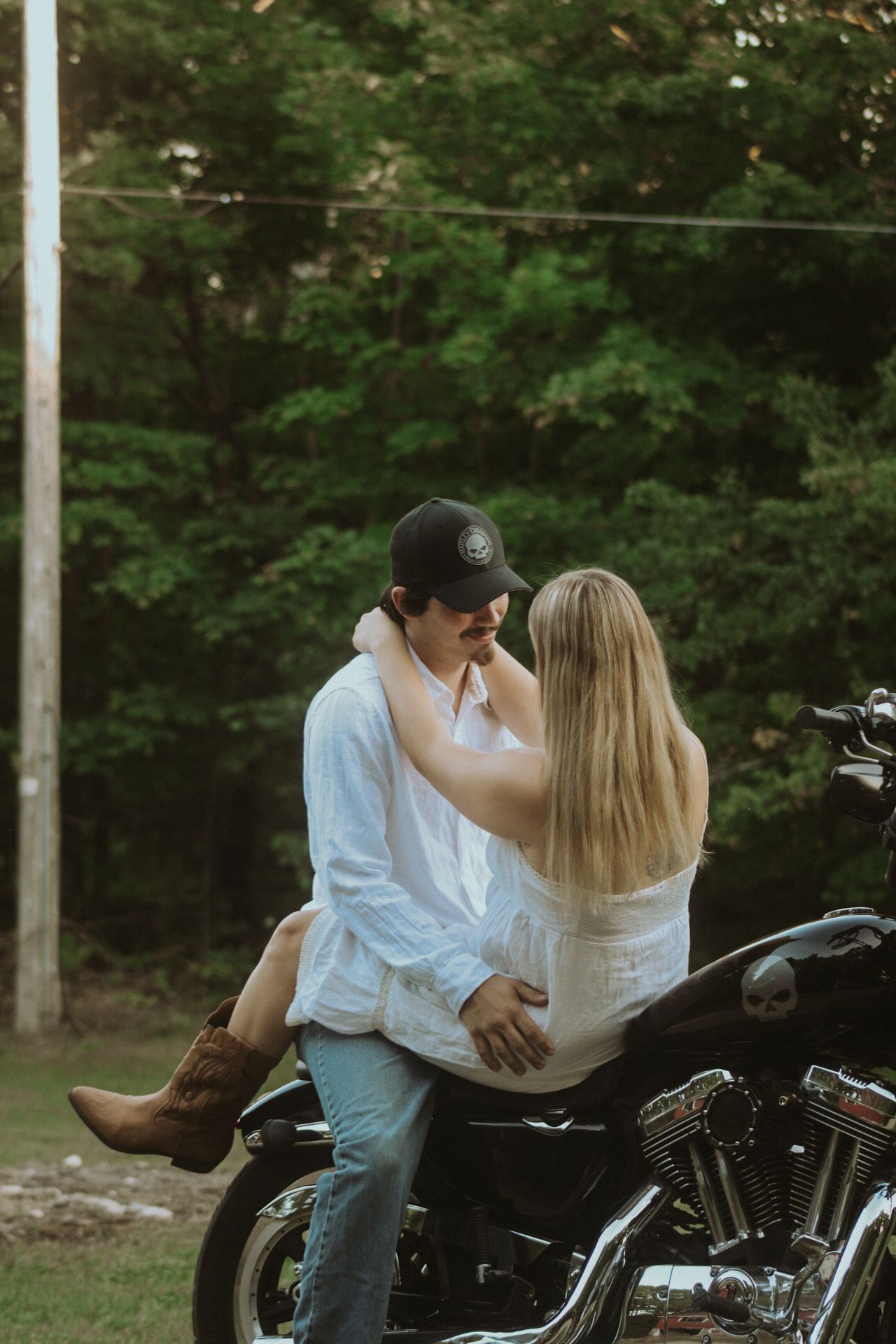 Romantic couple embracing on a motorcycle at dusk.