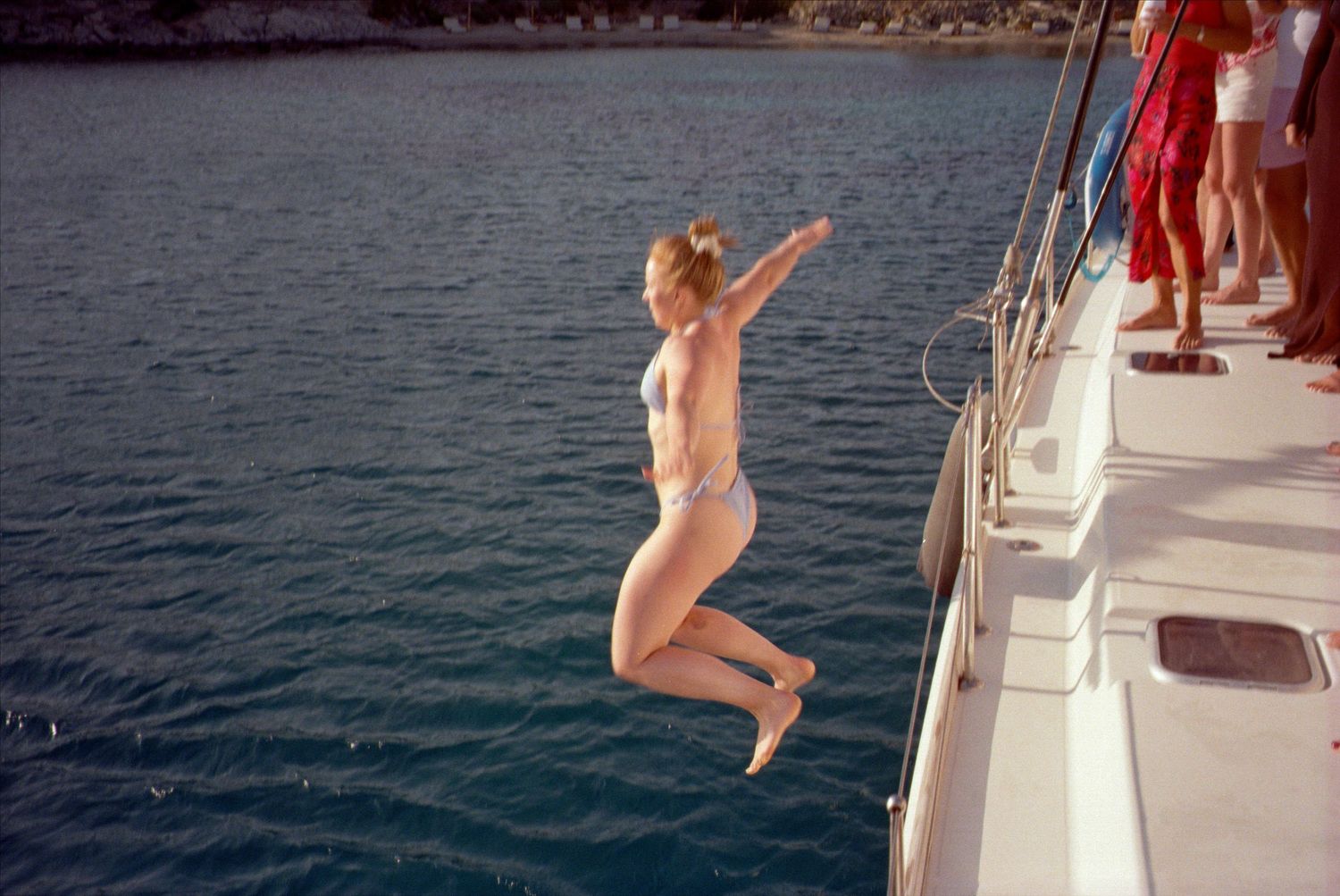 Four action shots show someone jumping off a boat into pristine blue waters on a sunny day.