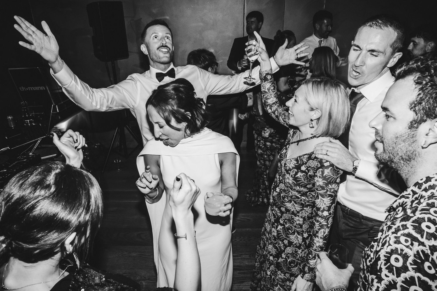 Black and white photo of energetic dancing and celebration at a wedding reception.