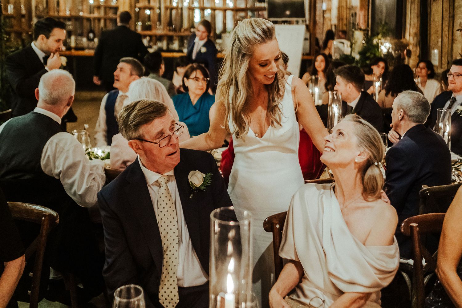 Wedding guests interact during intimate reception dinner in rustic venue setting.