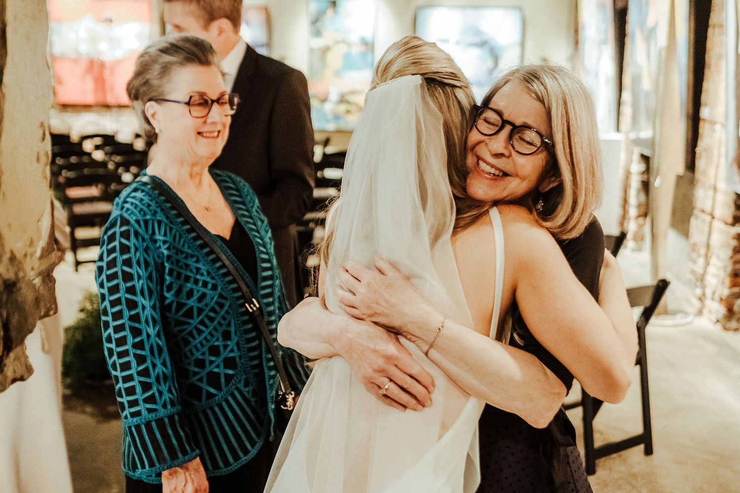 Warm embraces and celebrations with the bride at an indoor wedding reception.