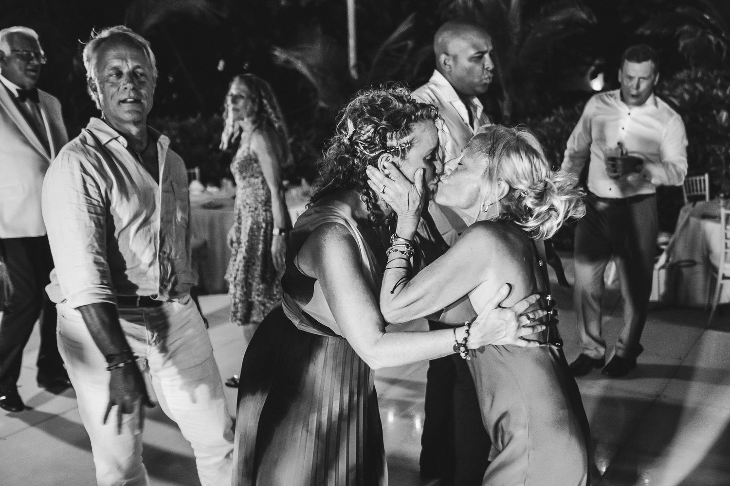 Energetic dancers move together on a dimly lit dance floor at a lively party celebration.